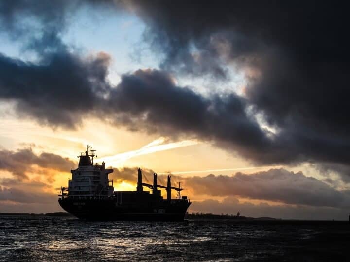 Et containerskib på havet ved solnedgang.